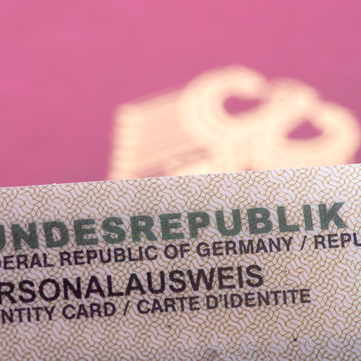 Darstellung der oberen Kante eines Personalausweises vor einem unscharf fotografierten Reisepass