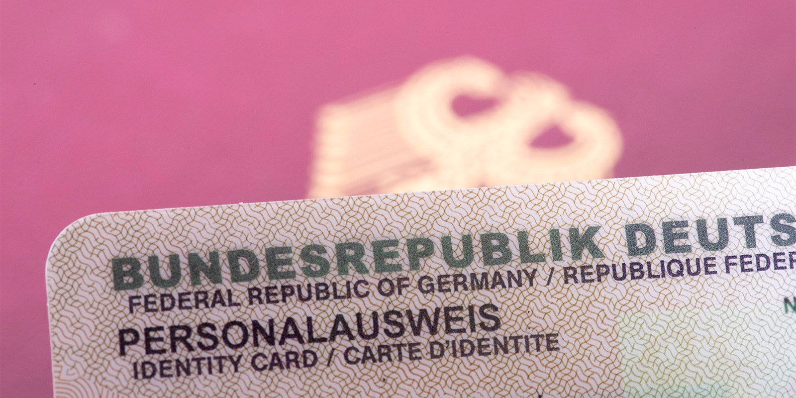 Darstellung der oberen Kante eines Personalausweises vor einem unscharf fotografierten Reisepass
