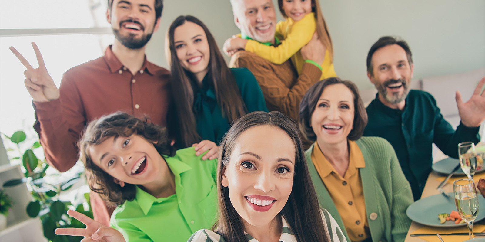 Eine Familie mit mehreren Generationen sitzt am Esstisch und macht ein Selfie zusammen