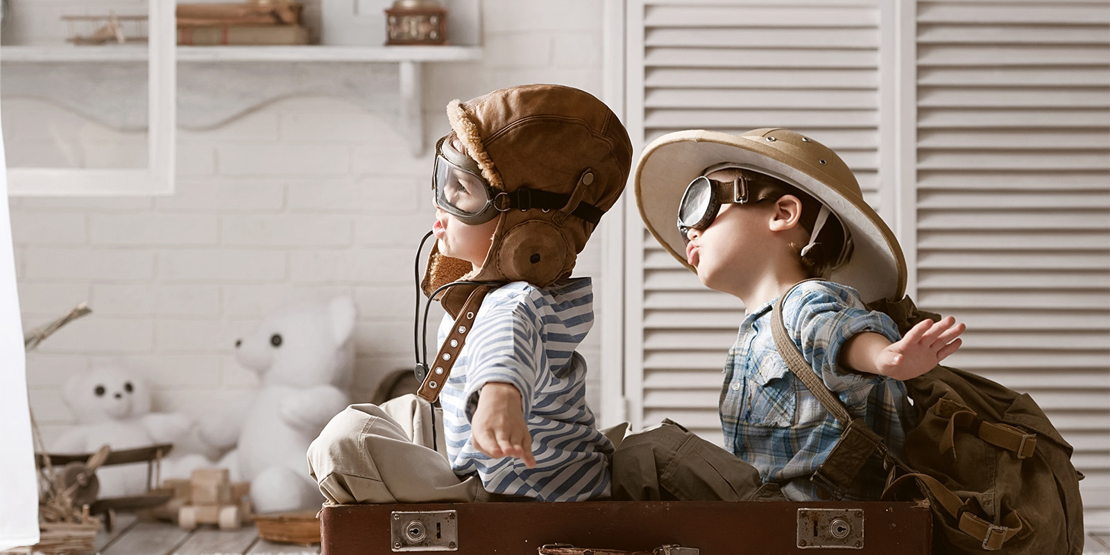 Zwei Kinder sitzen in einem Koffer und spielen Flugzeugpiloten
